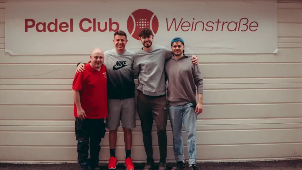 Dominique Heintz steht mit seinen Partnern vor dem Logo des Padel-Club Weinstraße.